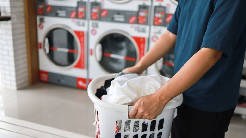 Man holding a bucket with clothes to be washed